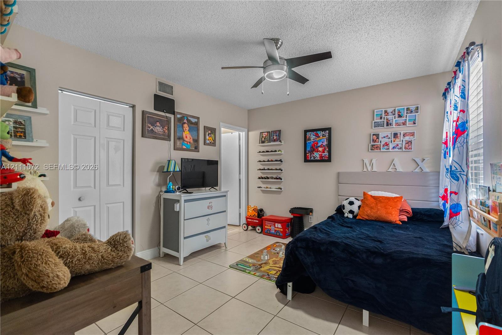 Room featuring large-format ceramic tile flooring, a multi-blade ceiling fan with integrated lighting, and dual-panel closet doors