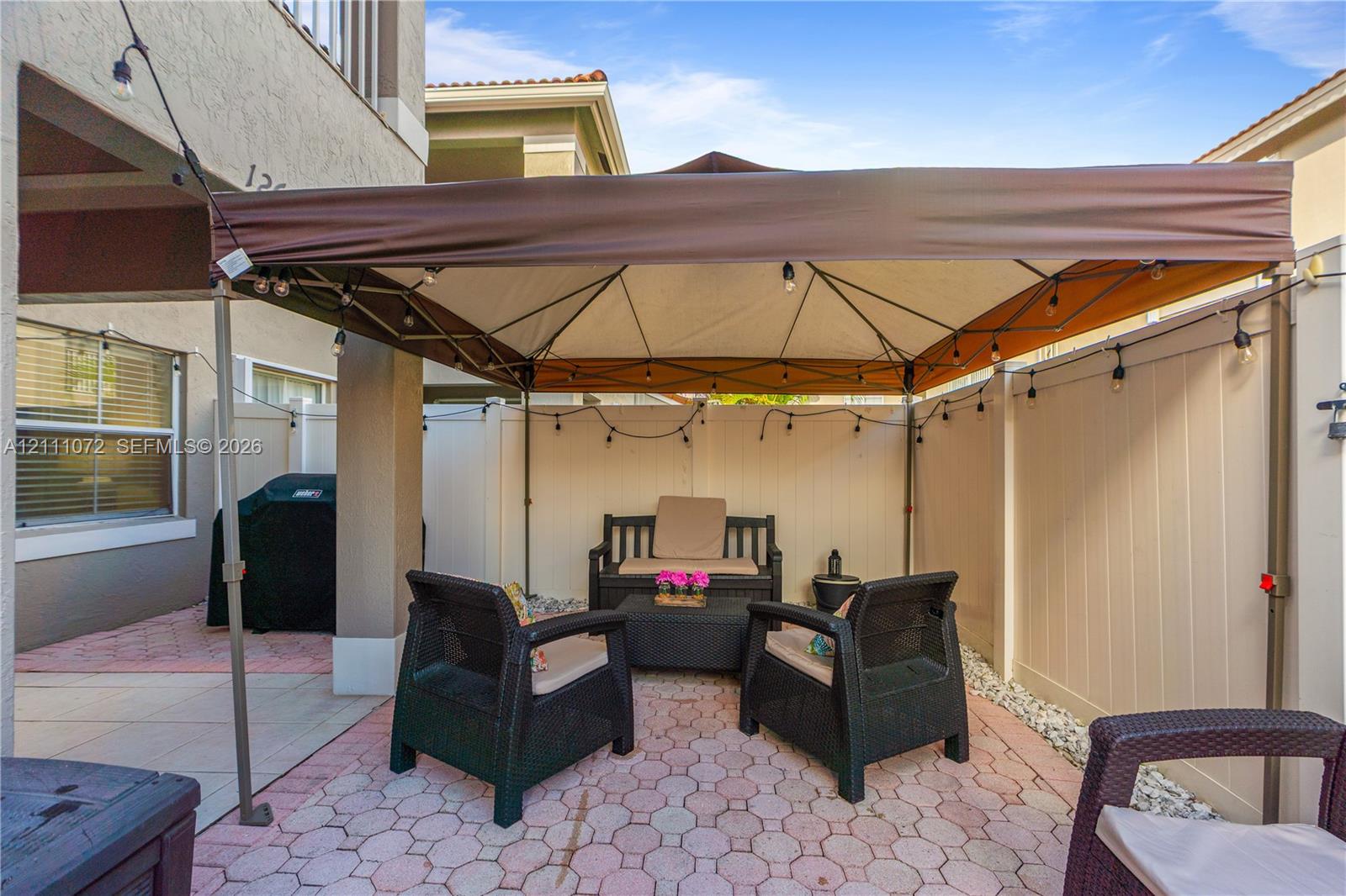 Paved patio space featuring a solid privacy fence, decorative stone pavers, and a covered architectural pillar