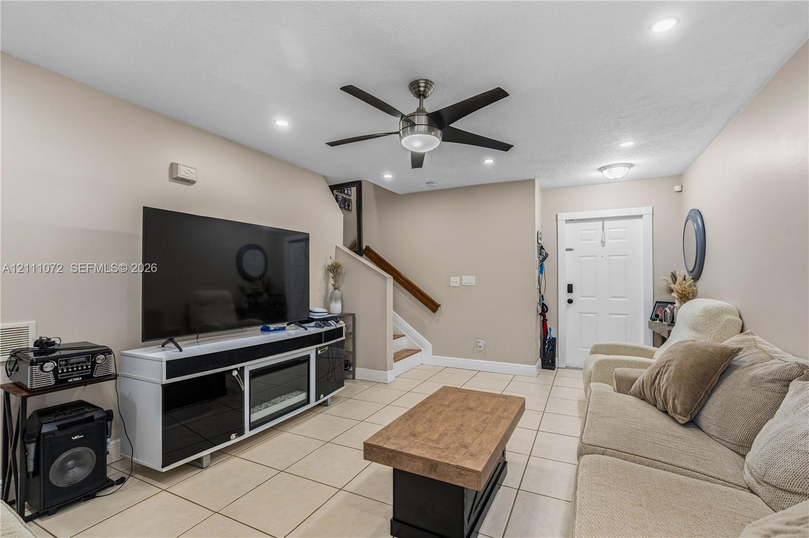 Living area featuring light-toned tile flooring, recessed lighting, a modern ceiling fan, and a built-in electric fireplace console