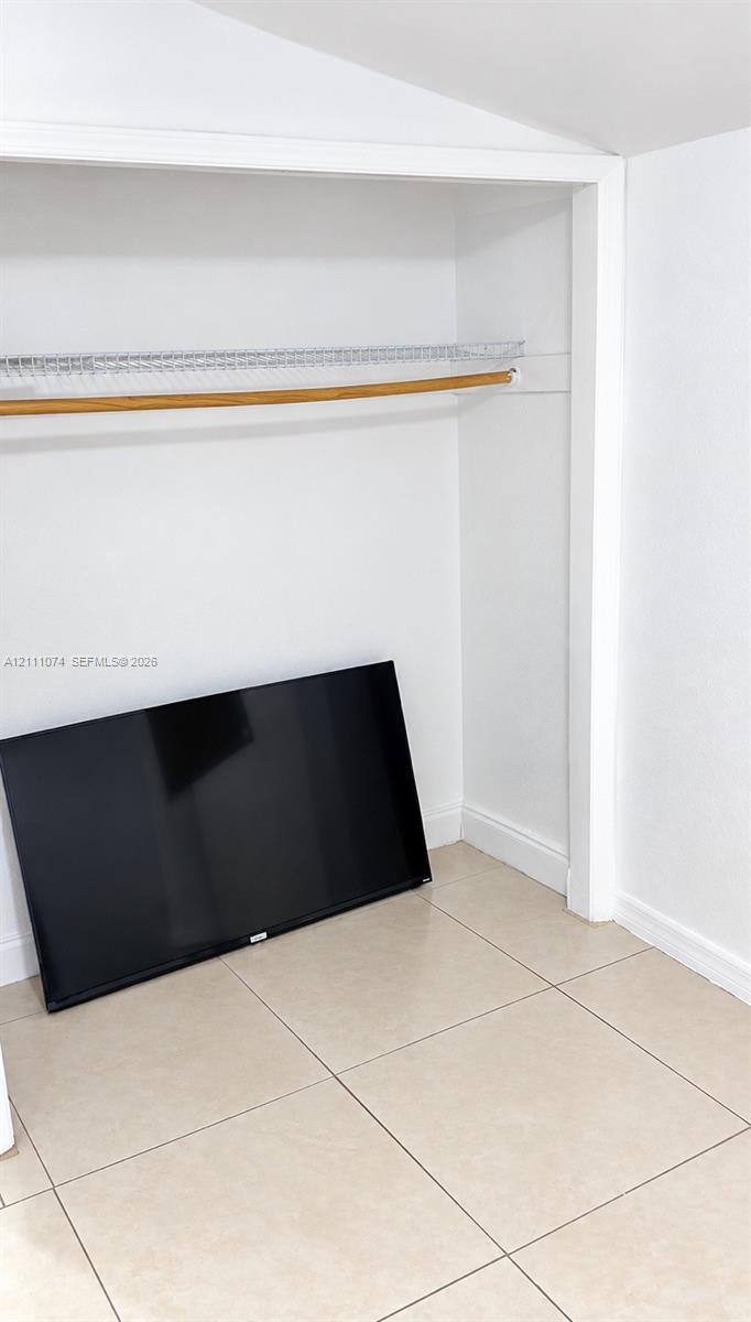 Closet featuring large-format ceramic floor tile, white-finished walls, and a built-in wire shelving system with a wood-finish hanging rod