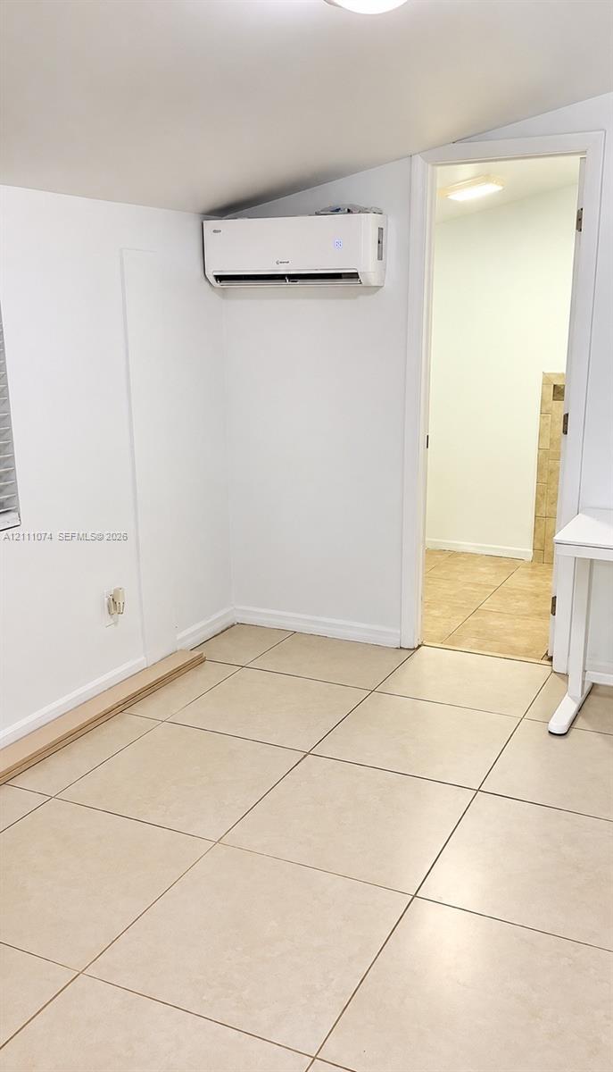 Wall-mounted ductless climate control system, neutral ceramic tile flooring, and vaulted ceiling