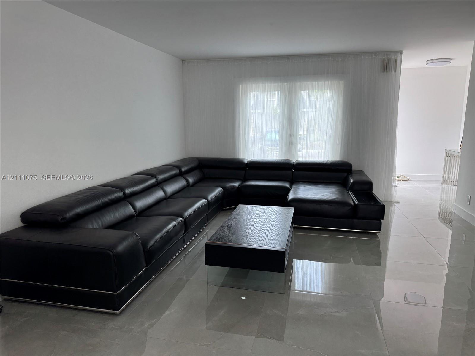 Large format light-colored tile flooring, double glass panel doors, and neutral wall tones Large format light-colored tile flooring, double glass panel doors, and neutral wall tones