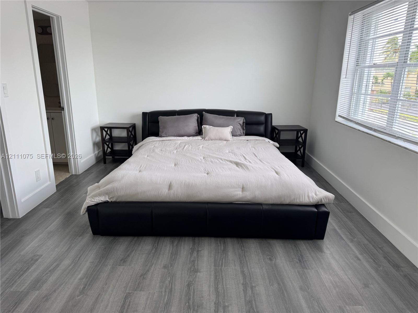 Room featuring wood-finish flooring, neutral walls, and a window with horizontal blinds