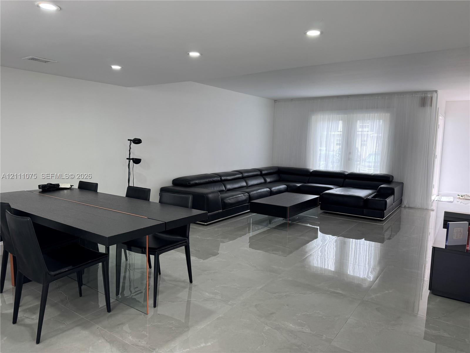 Polished large-format floor tile, recessed ceiling lighting, and floor-to-ceiling sheer window treatments Polished large-format floor tile, recessed ceiling lighting, and floor-to-ceiling sheer window treatments