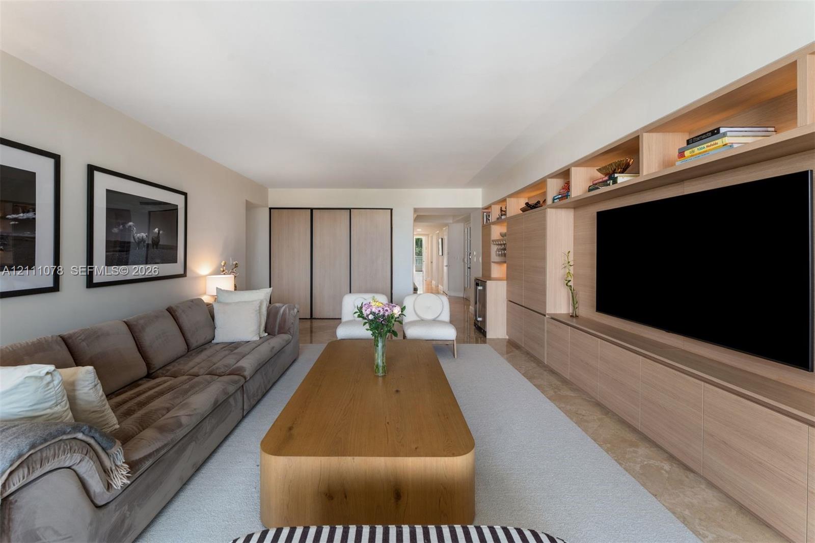 Custom wood-finish built-in media cabinetry with integrated shelving, recessed lighting, and stone flooring