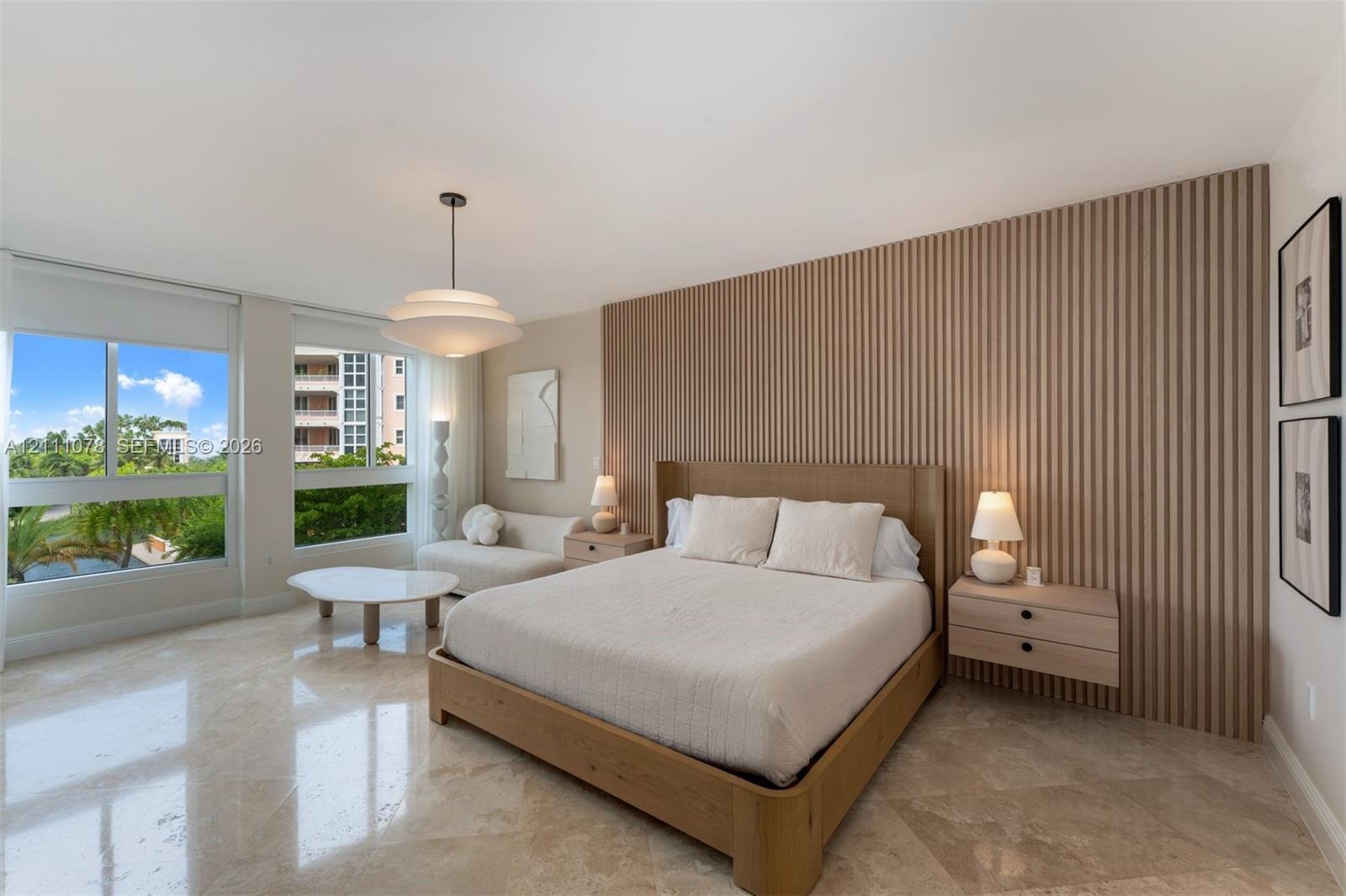 Bedroom featuring polished stone flooring, a floor-to-ceiling slatted wood accent wall, floating wood-finish nightstands, and expansive horizontal windows