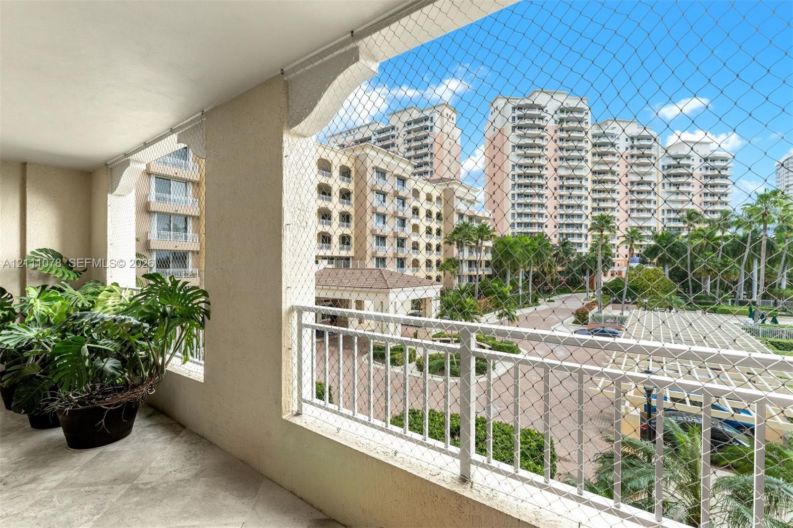 Covered balcony featuring stone-finish flooring, decorative corbel accents, and a protective mesh screen enclosure