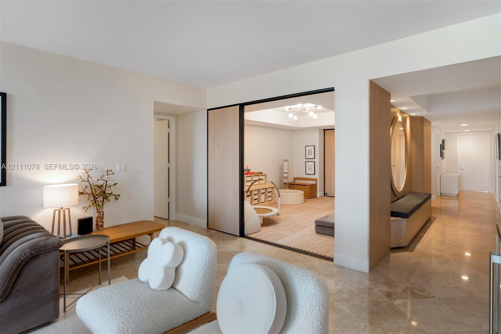 Interior space featuring polished stone flooring, custom wood-paneled sliding room divider with black framing, built-in recessed bench seating with circular mirror, and recessed ceiling lighting
