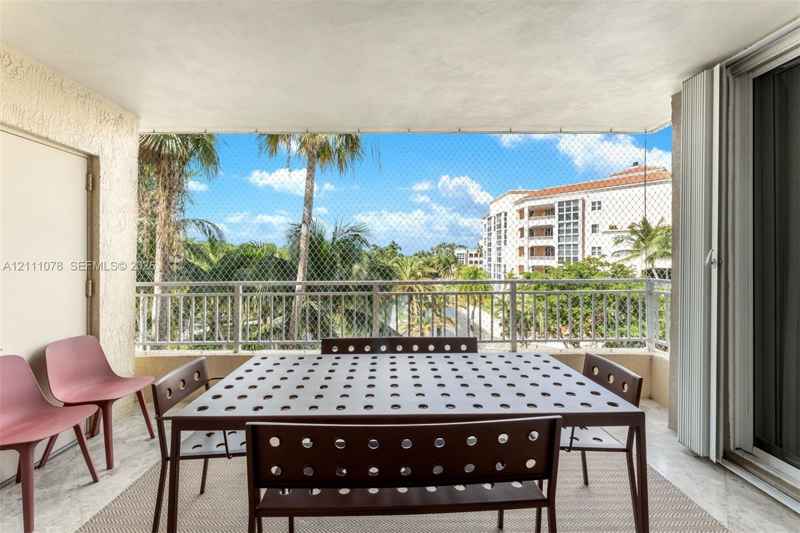 Covered balcony featuring stone flooring, white metal railing, and protective mesh screening