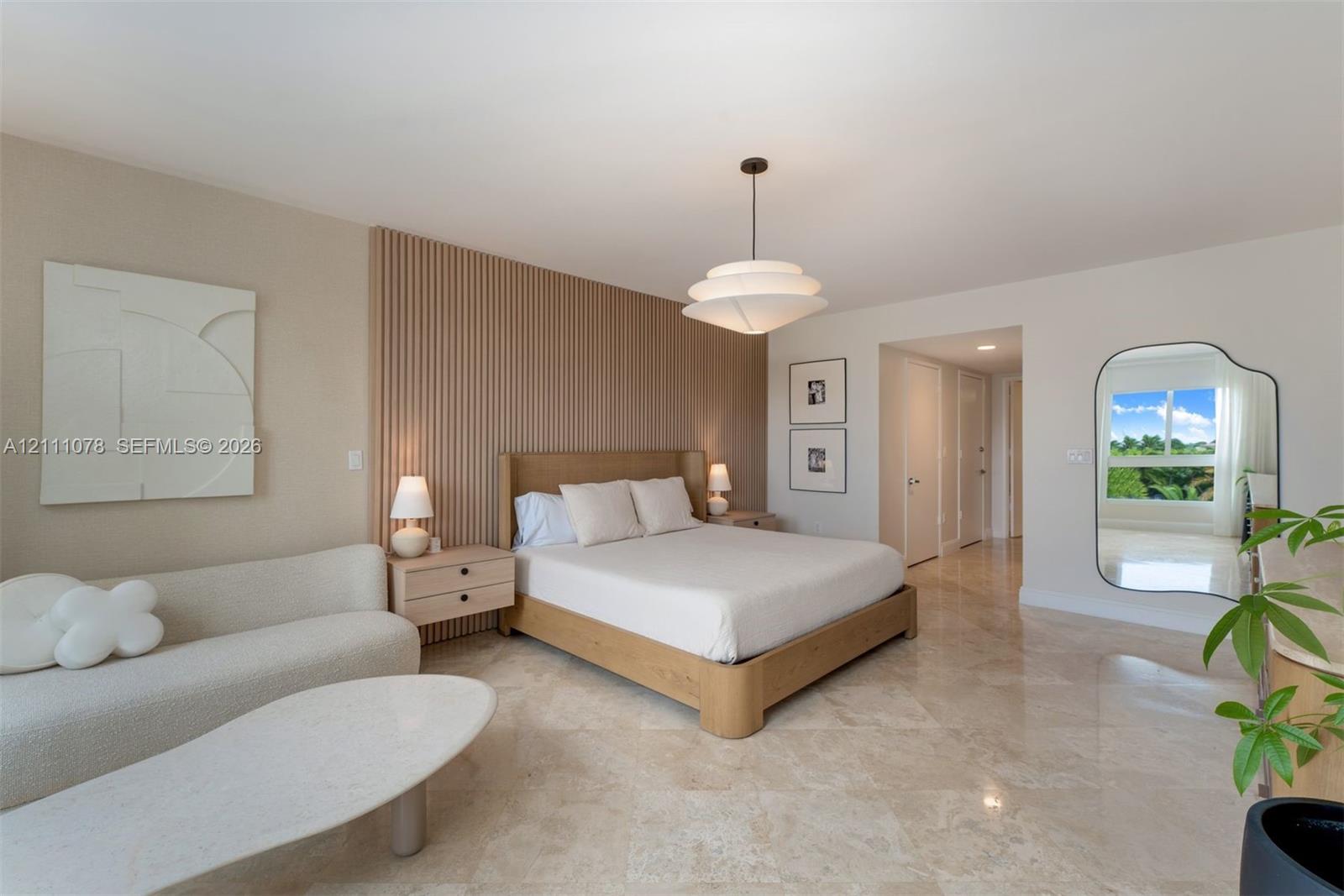 Interior space featuring polished stone flooring, custom vertical wood-slat accent wall, and multi-tiered modern pendant lighting