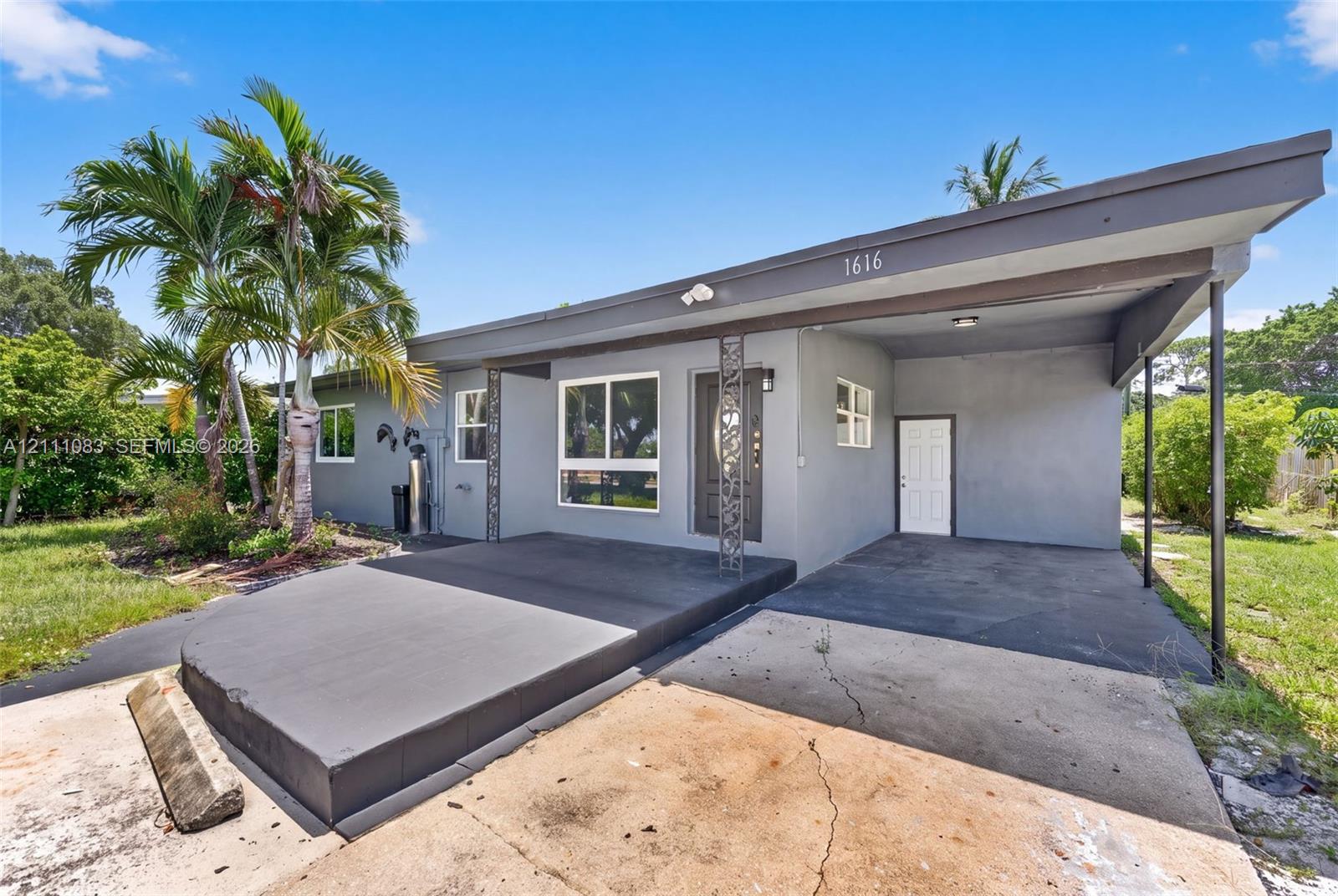 Mid-century modern exterior featuring a flat roofline, attached covered carport, decorative metal porch pillars, and a concrete patio Mid-century modern exterior featuring a flat roofline, attached covered carport, decorative metal porch pillars, and a concrete patio