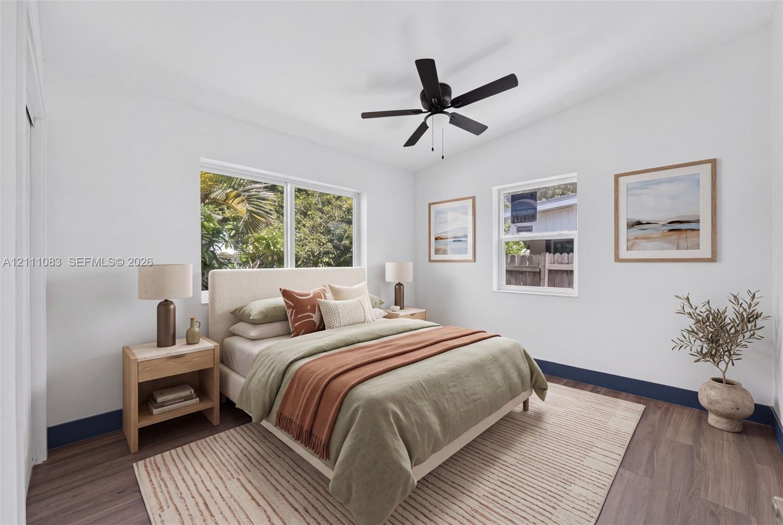 Neutral-toned interior featuring wood-finish flooring, a matte black ceiling fan with integrated lighting, and multiple vinyl-framed windows
