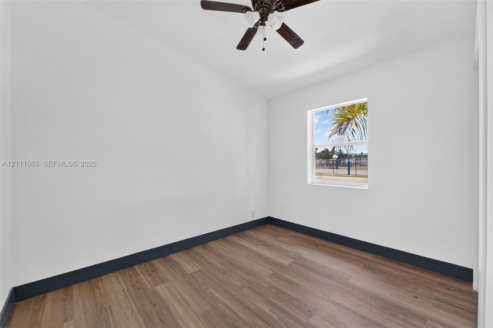 Room featuring wood-finish flooring, a single-hung window, and a ceiling fan with integrated lighting