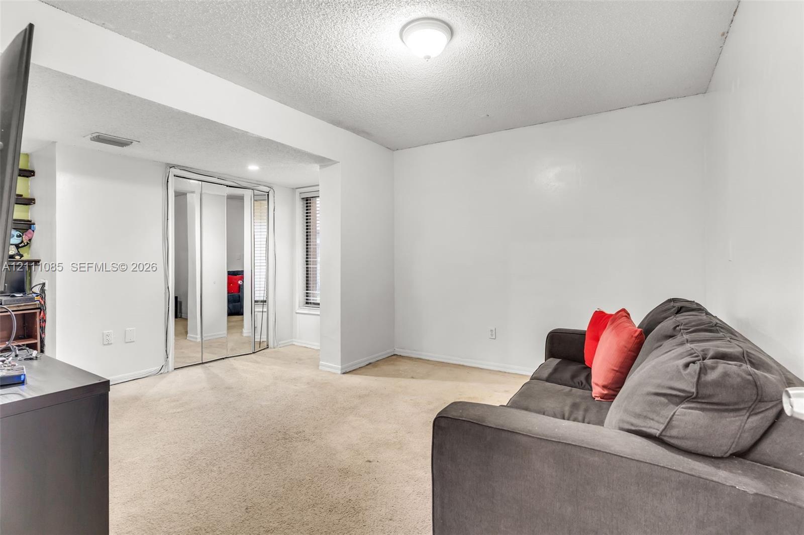 Neutral-toned interior space featuring wall-to-wall carpeting, floor-to-ceiling mirrored closet doors, and recessed window framing