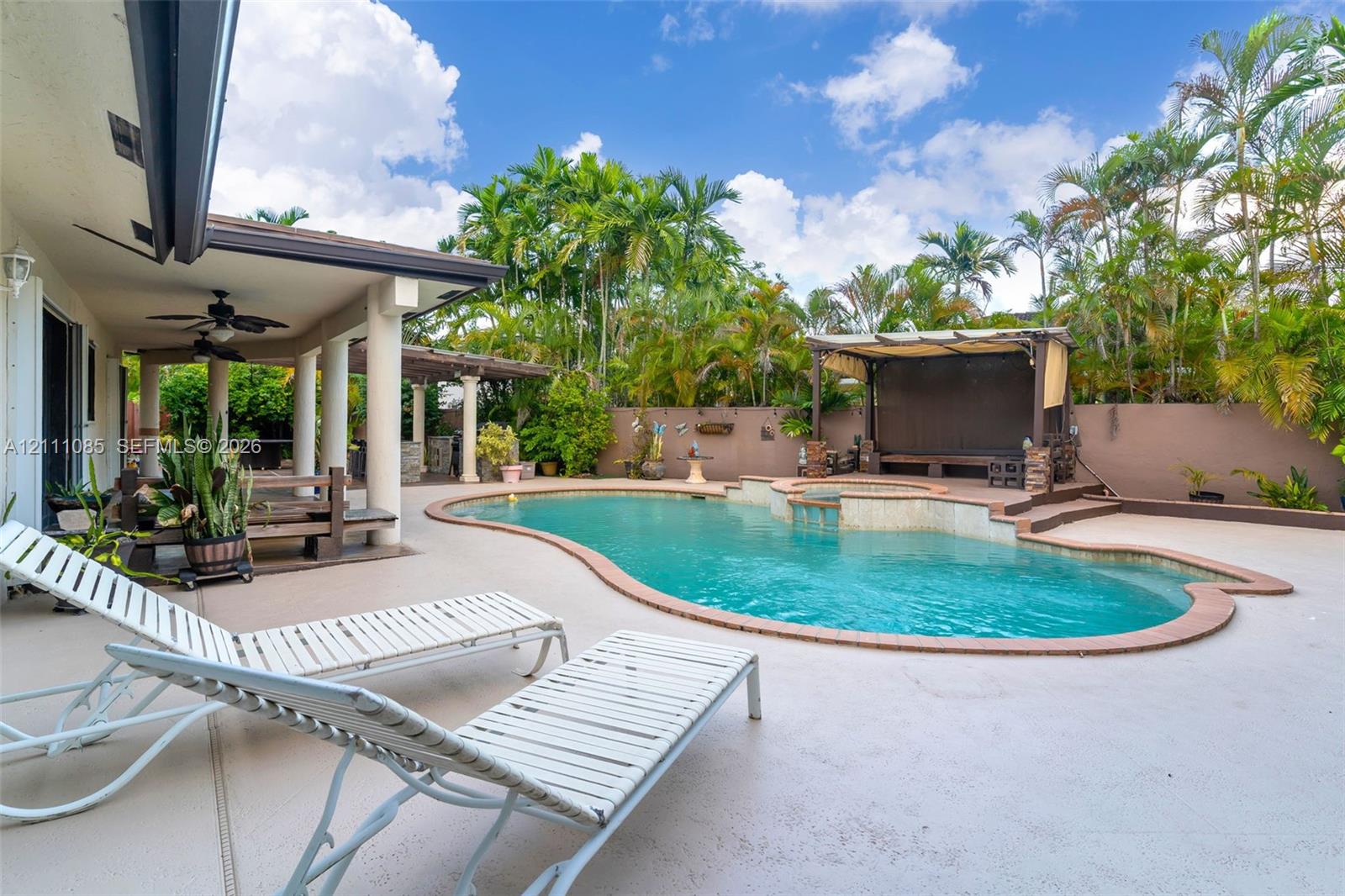 Outdoor space featuring a freeform swimming pool with integrated spa, covered patio with structural columns, and elevated wooden deck structure with canopy