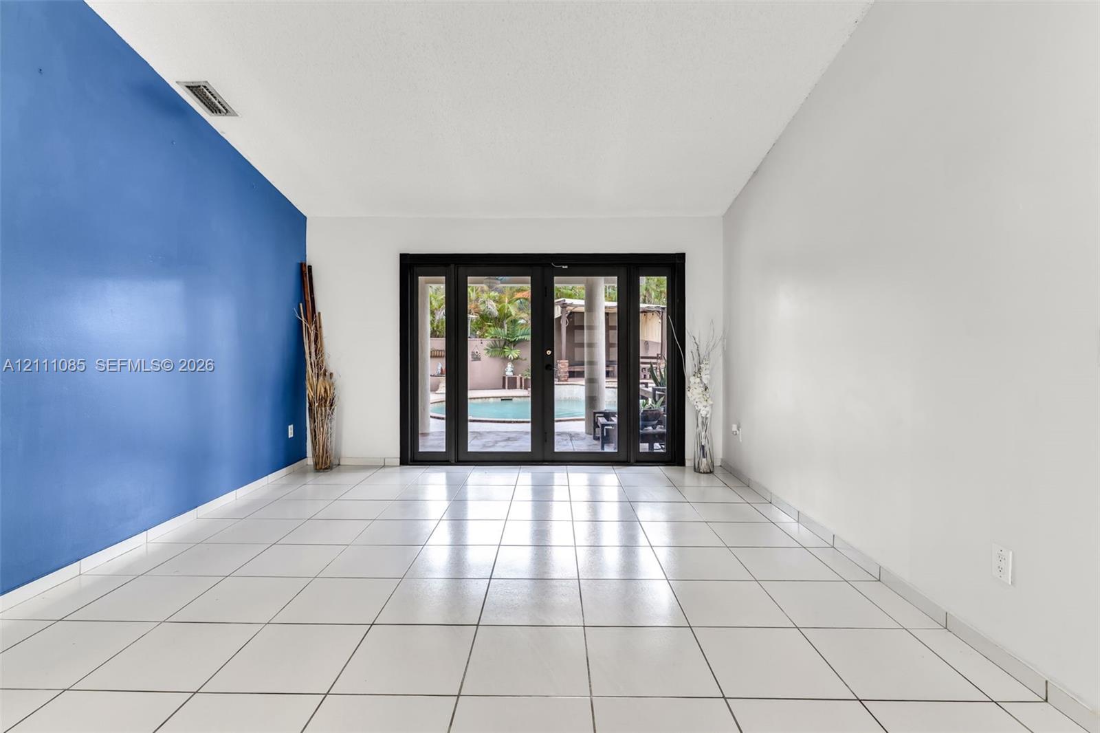 Interior space featuring large-format tile flooring, vaulted ceilings, and multi-panel glass exterior doors