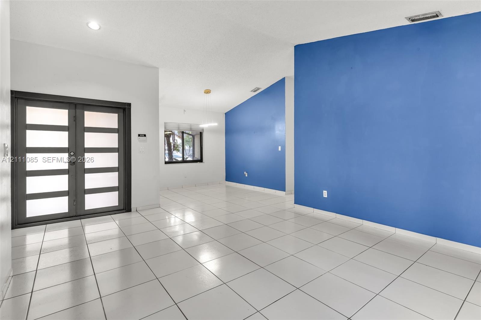 Entry featuring double doors with glass panel inserts, white ceramic tile flooring, recessed ceiling lighting, and vaulted ceilings