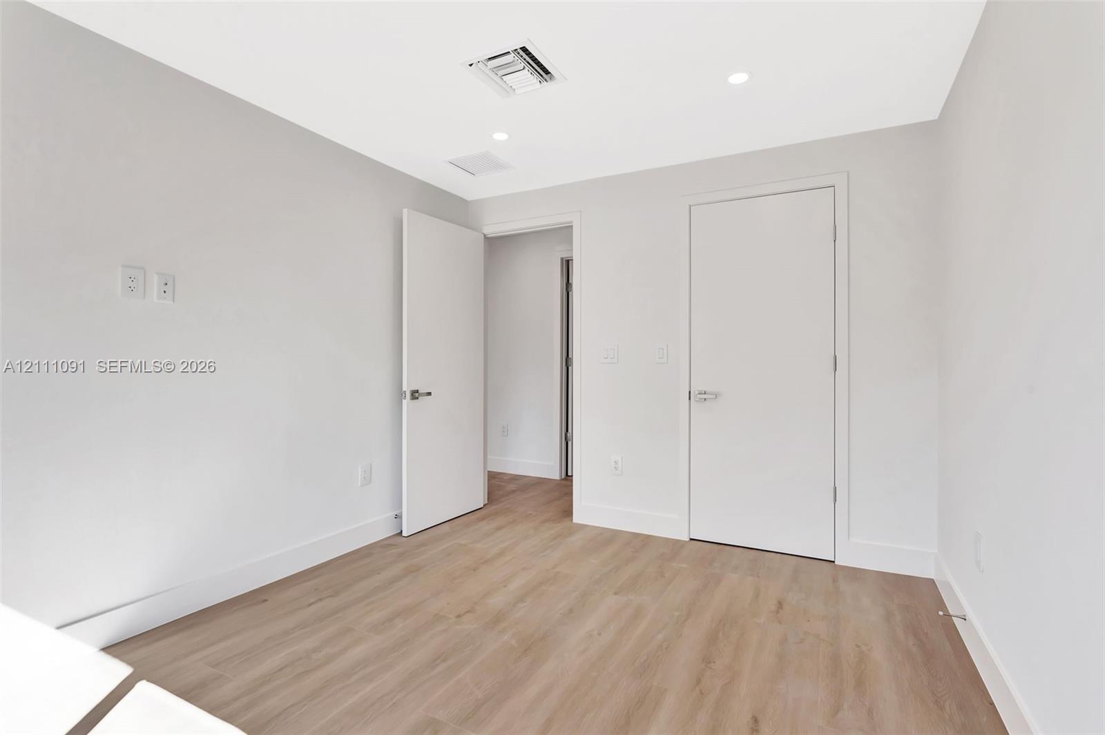 Neutral-toned interior featuring wood-finish flooring, recessed lighting, and solid-core doors