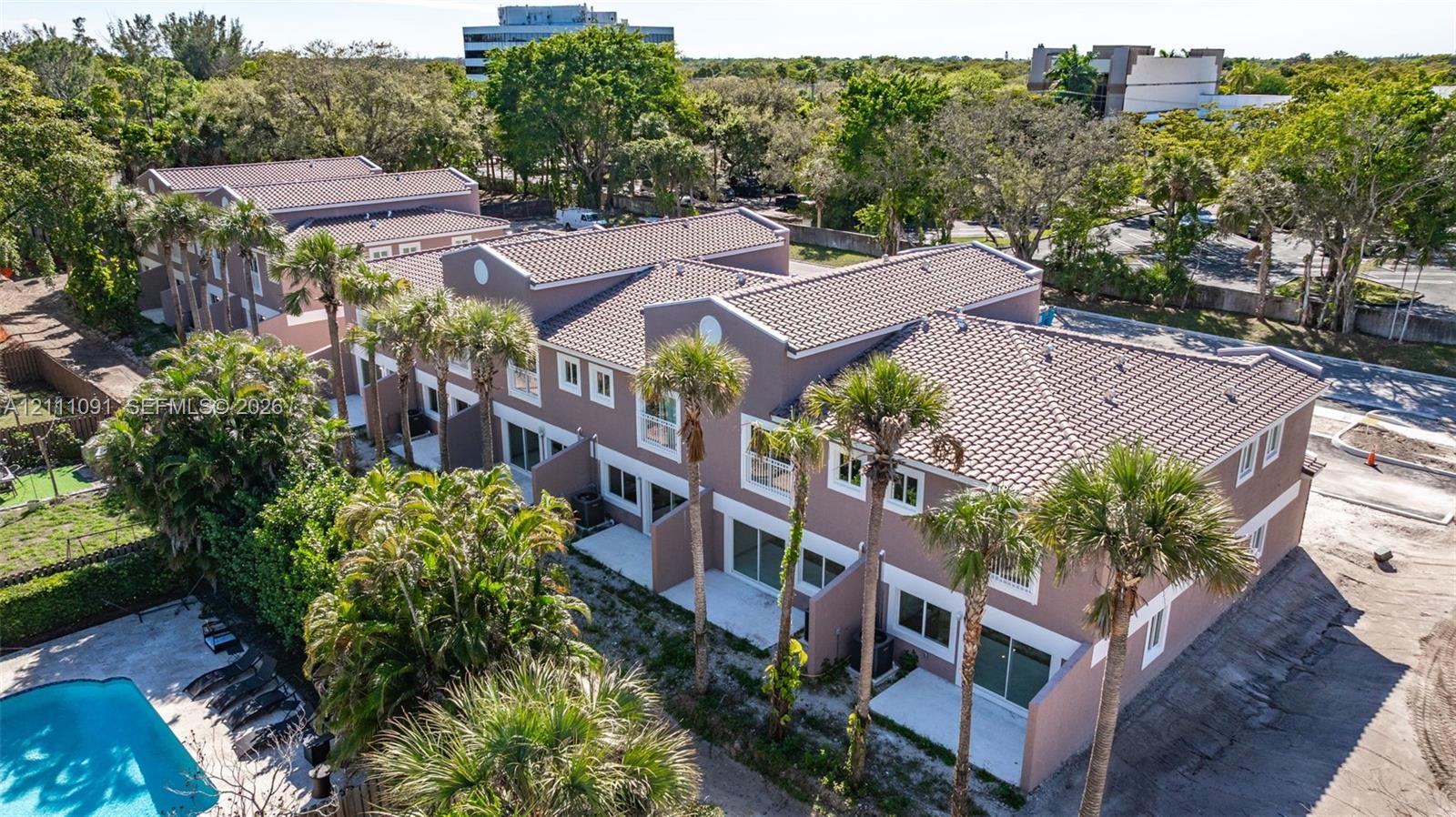 Multi-level townhouse complex with tile roofing, exterior concrete patios, and established palm tree landscaping