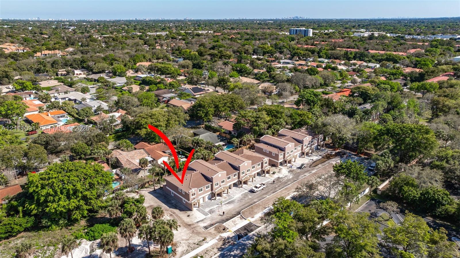 Aerial perspective of a multi-unit residential structure featuring a tiled roof, stucco exterior, and paved driveway access