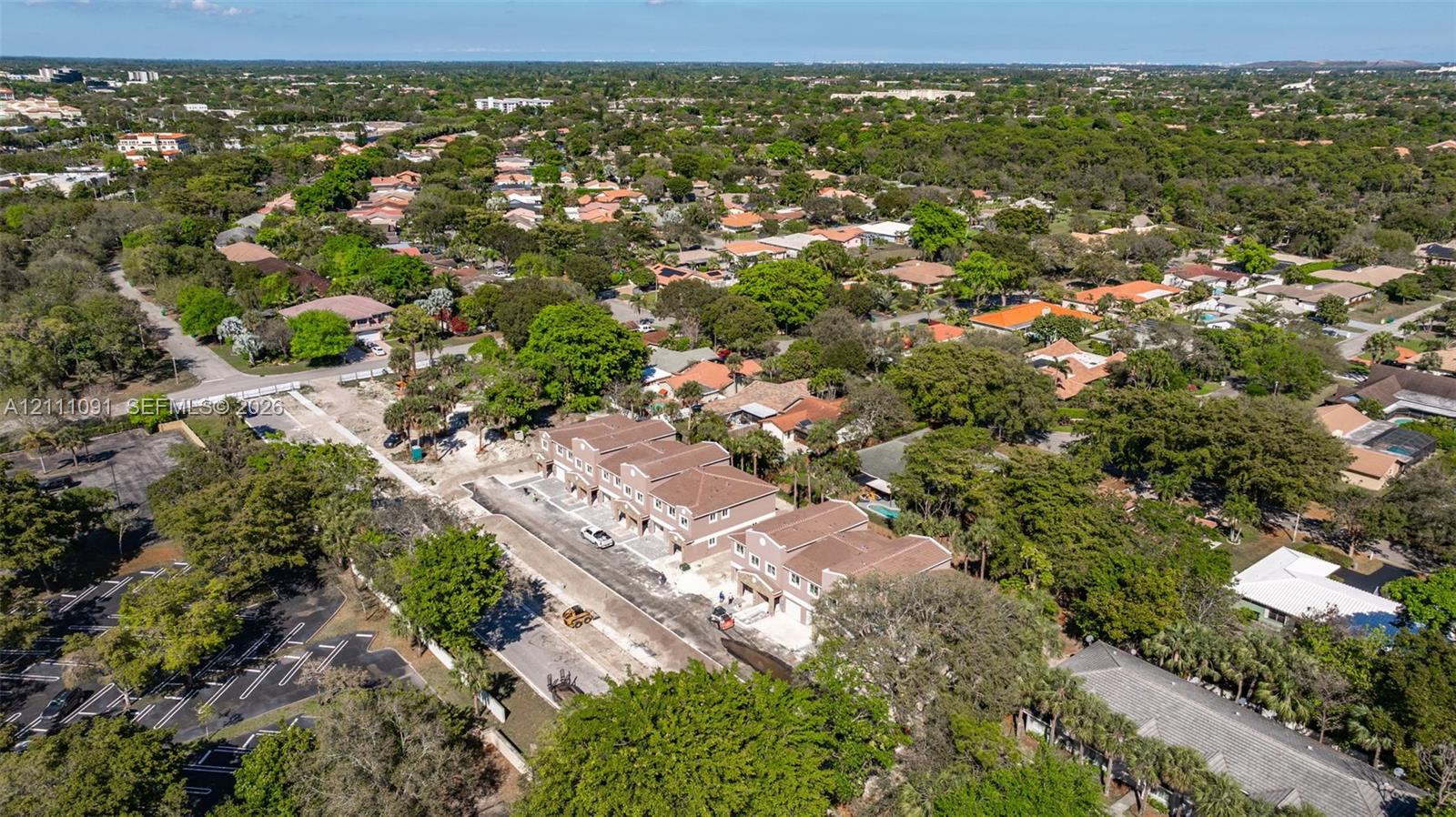 Aerial perspective featuring multi-story residential structures with tile roofs and paved street access