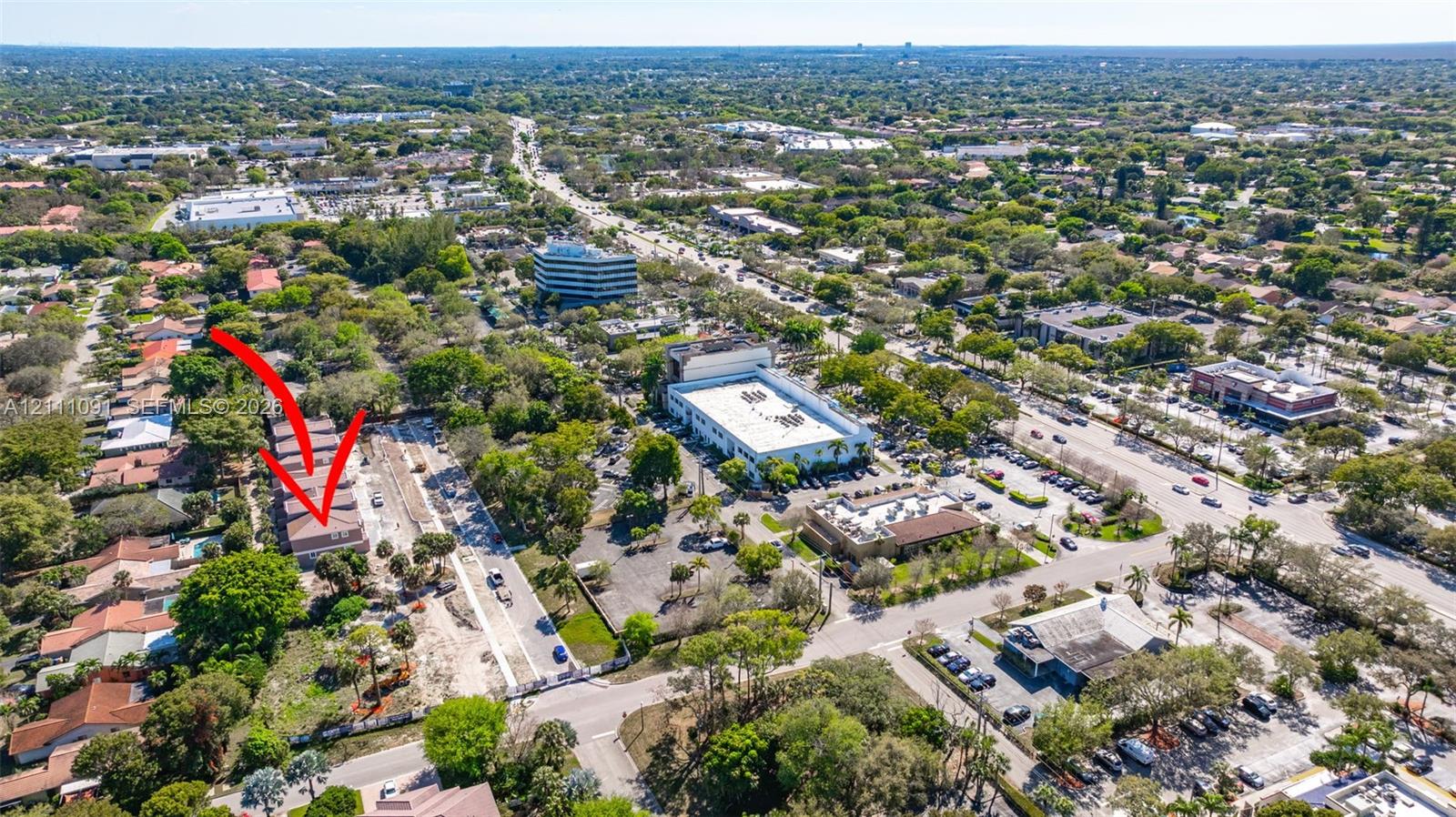 Aerial perspective of a multi-story residential structure featuring a tile roof, light-toned exterior finish, and established surrounding vegetation