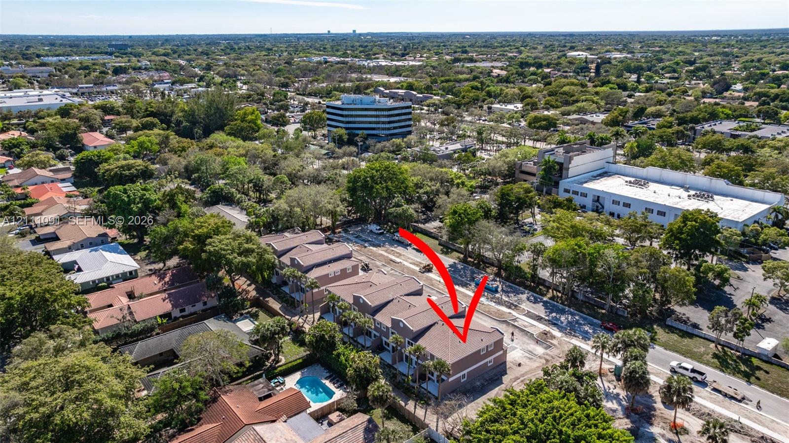 Aerial view of a multi-story residential structure featuring a pitched roof, exterior balconies, and palm tree landscaping
