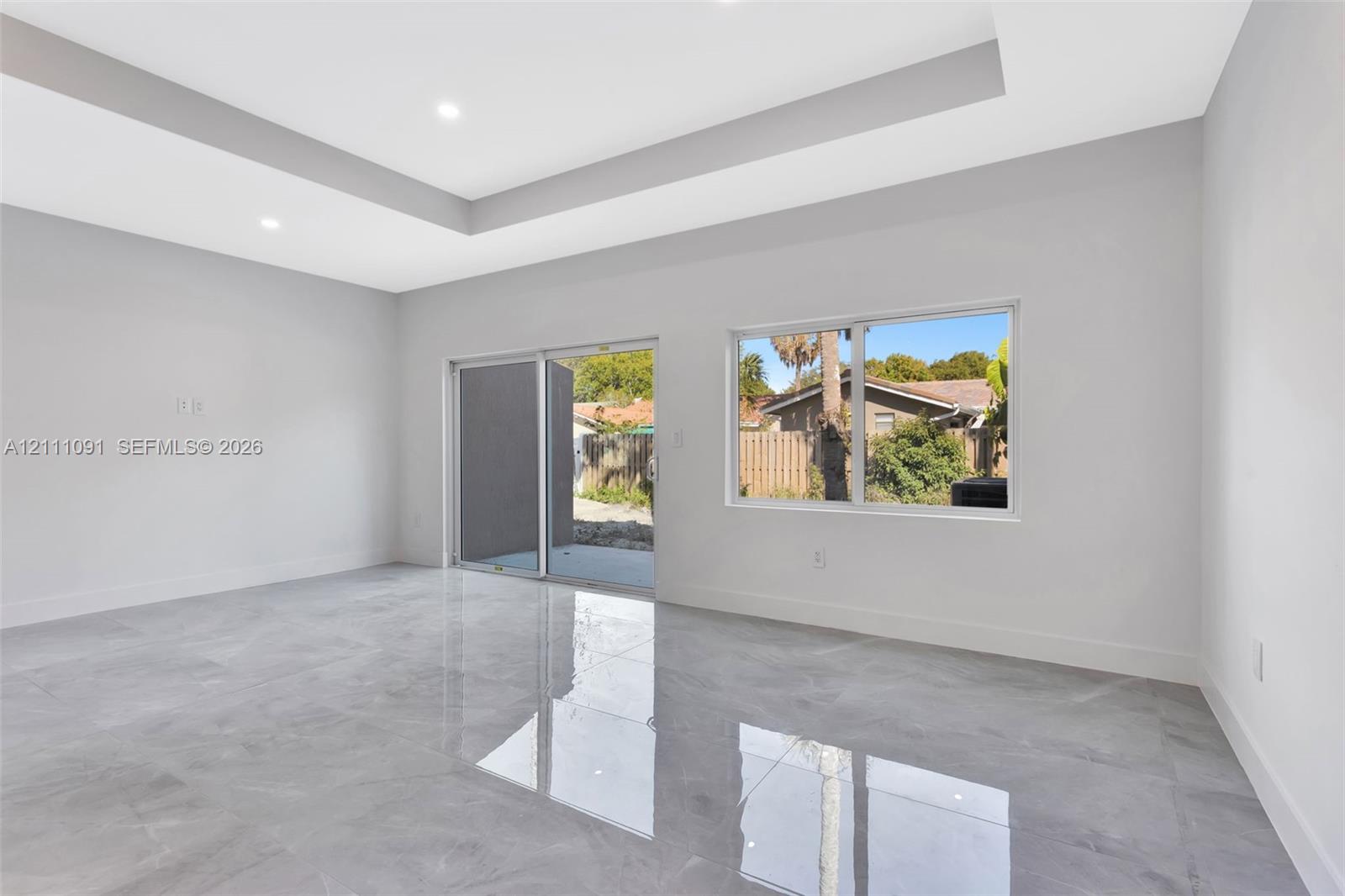 Tray ceiling with recessed lighting, large-format tile flooring, sliding glass door, and picture window