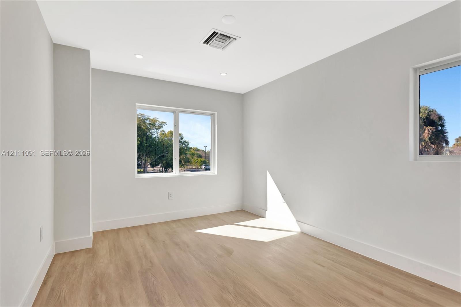 Neutral interior space featuring wood-finish flooring, recessed lighting, and multiple windows