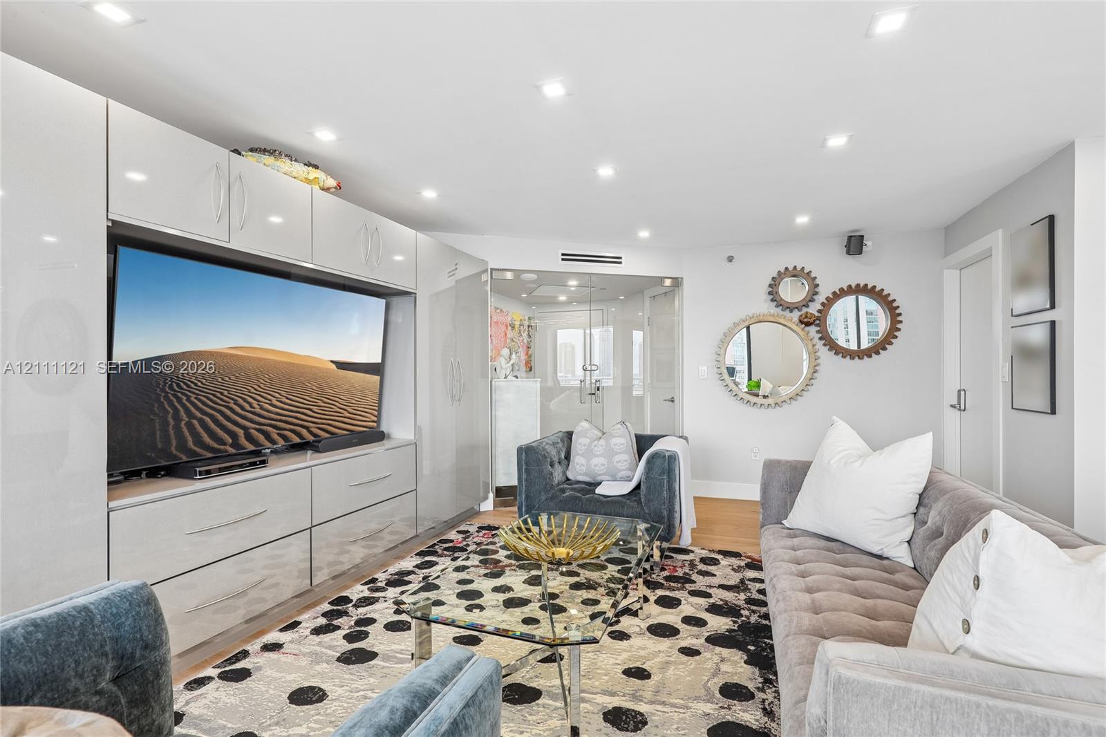 Built-in high-gloss cabinetry, recessed ceiling lighting, and glass-enclosed entry