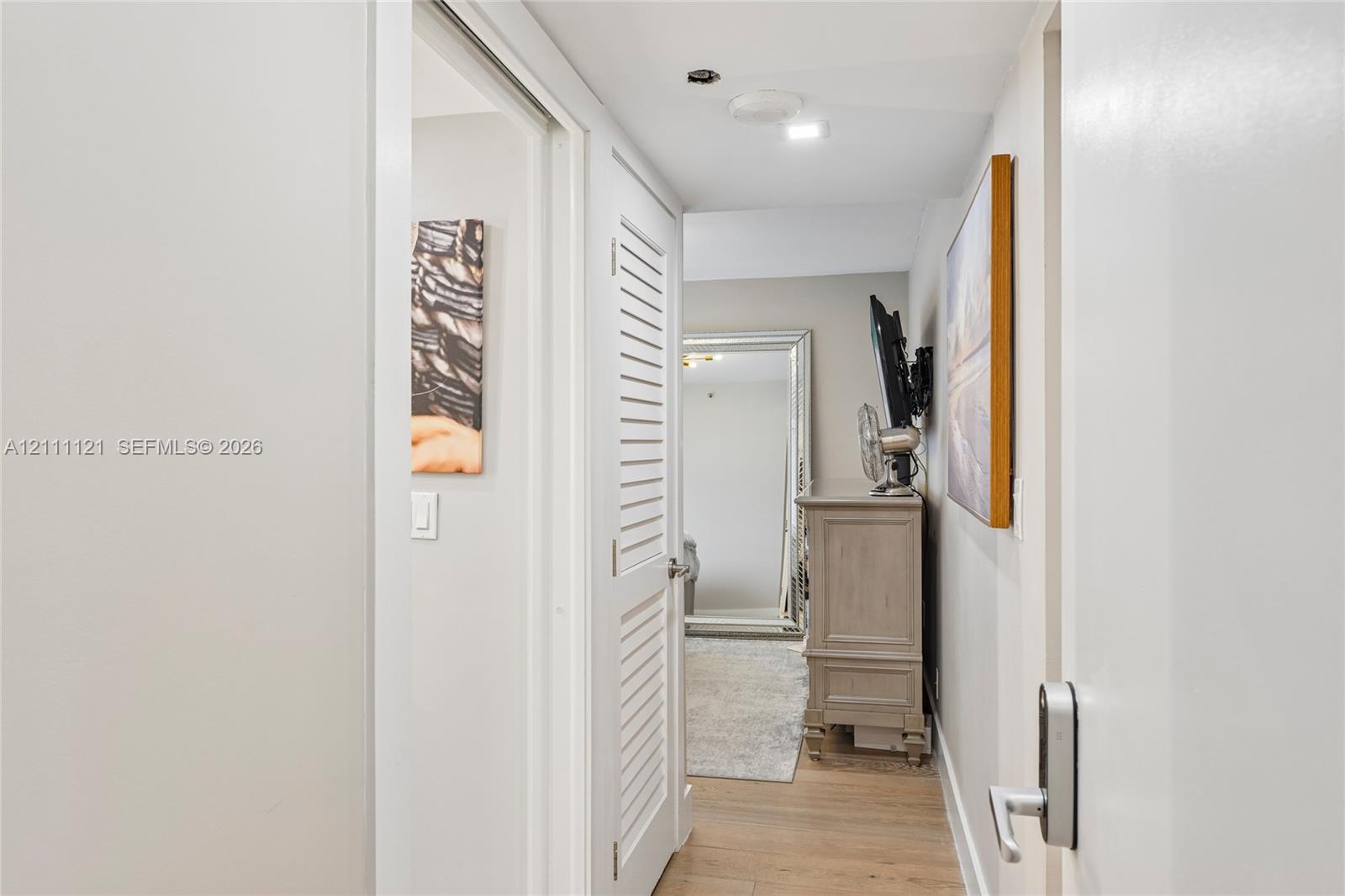 Louvered door, wood-finish flooring, and recessed ceiling lighting entry to guest bedroom