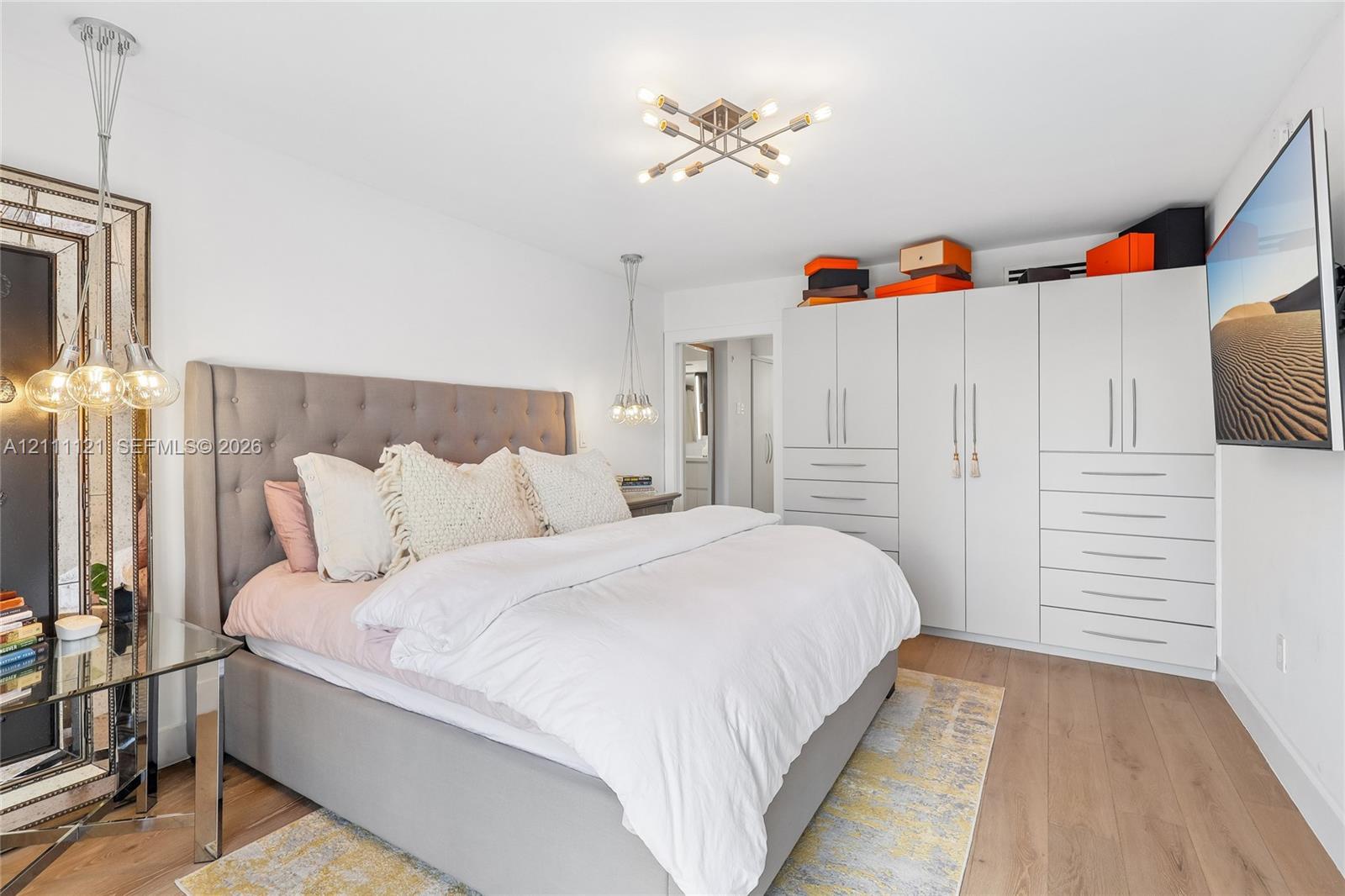 Room featuring wood-finish flooring, built-in floor-to-ceiling cabinetry, multi-light ceiling fixture, and dual hanging pendant lights