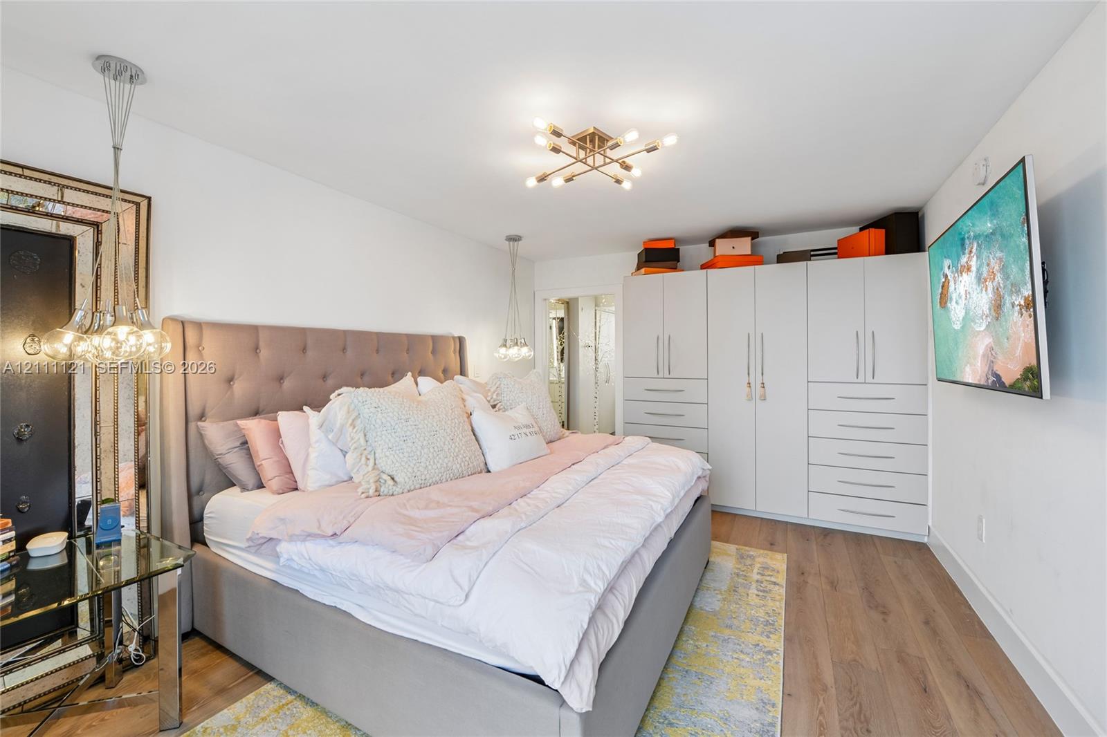 Wood-finish flooring, built-in floor-to-ceiling cabinetry, multi-bulb central ceiling lighting, and pendant fixtures