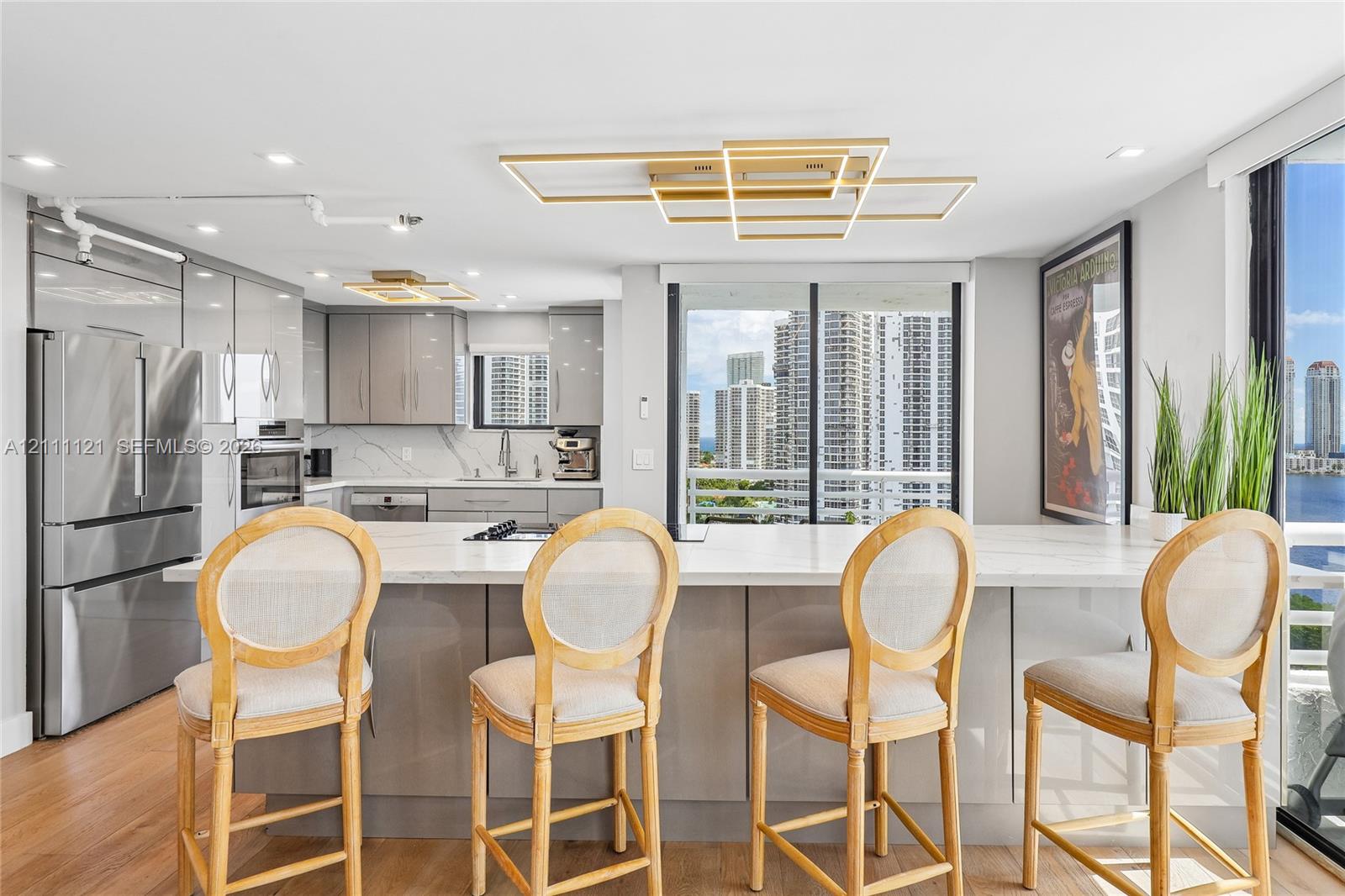 Kitchen featuring a central island with a stone-surface countertop, high-gloss cabinetry, stainless steel appliances, and contemporary geometric ceiling lighting