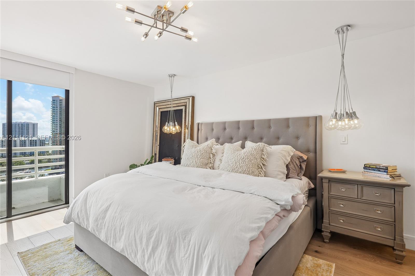 Multi-light modern chandelier, adjustable pendant lighting, wood-finish flooring, sliding glass door, and balcony