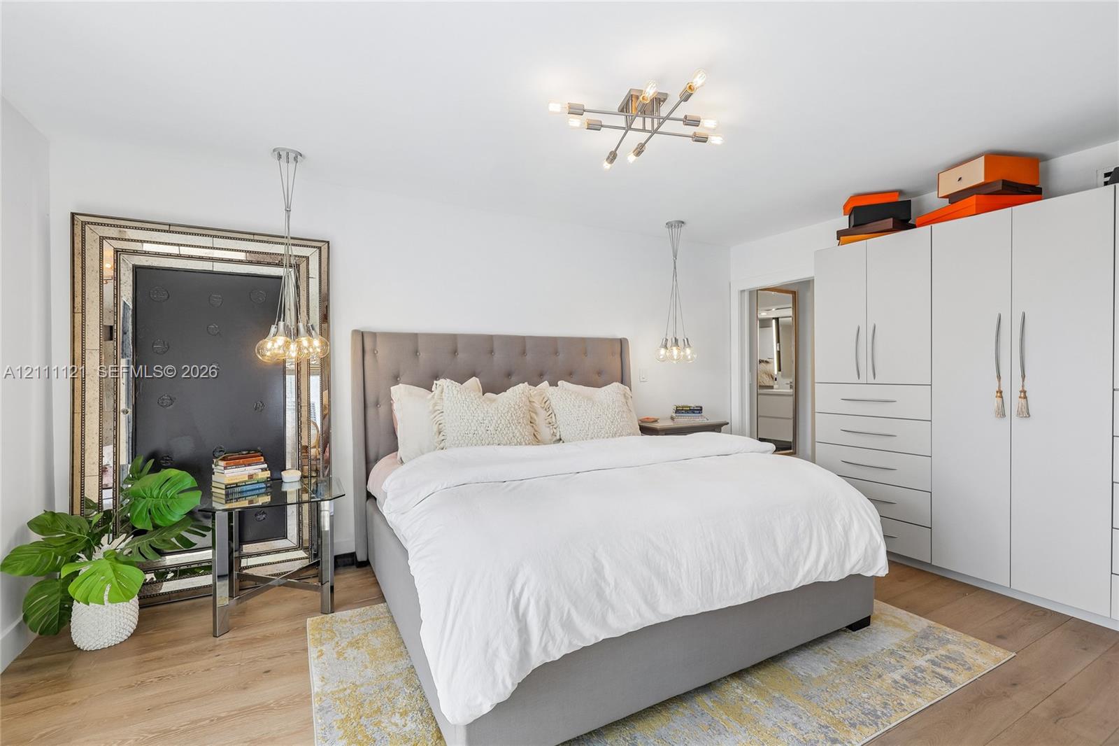 Floor-to-ceiling built-in cabinetry, wide-plank wood-finish flooring, multi-arm ceiling fixture, and dual pendant lights