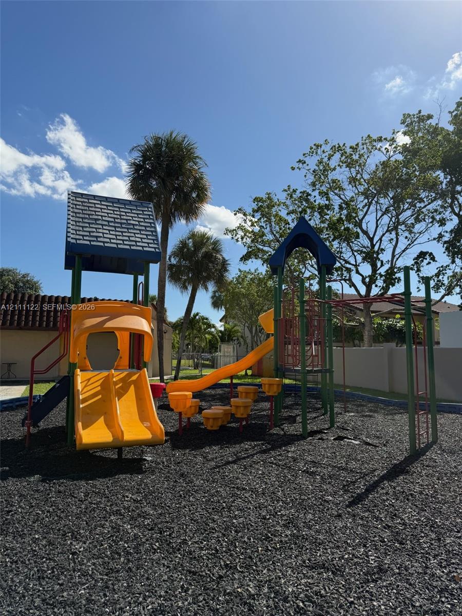 Outdoor recreational area featuring a multi-level climbing structure, dual slides, stepping platforms, and rubberized ground cover