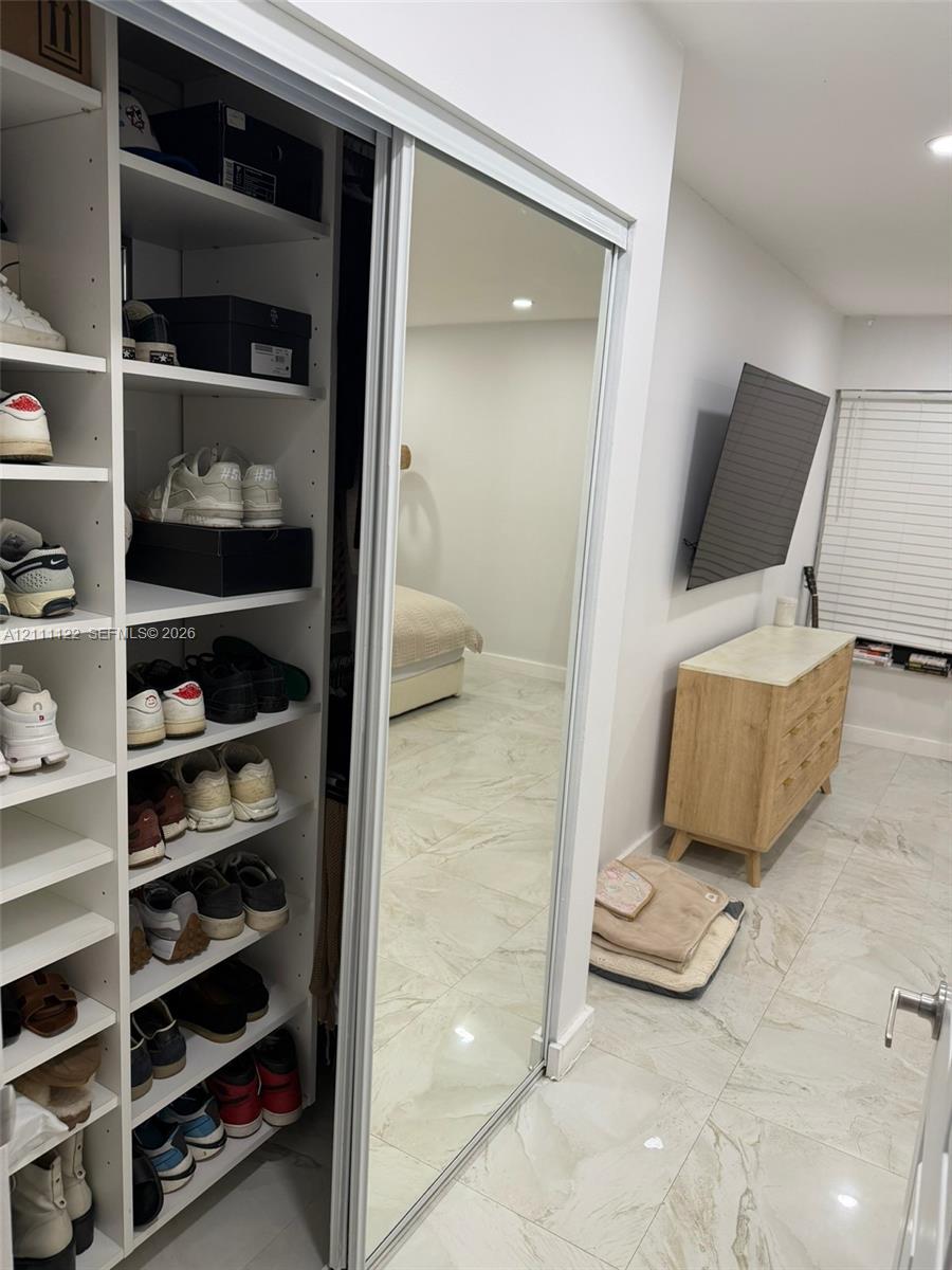 Built-in floor-to-ceiling shelving, sliding mirrored closet doors, and tile flooring