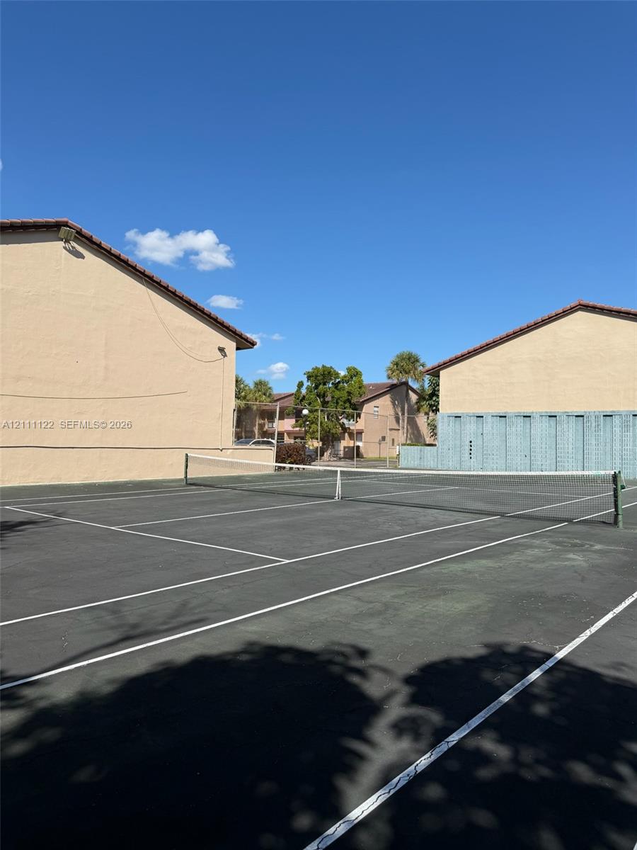 Hard-court tennis facility with painted boundary lines, permanent net, and perimeter fencing
