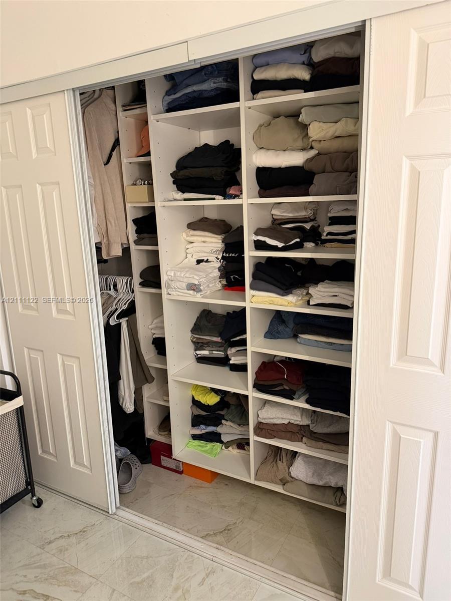 Custom built-in closet featuring white paneled sliding doors, floor-to-ceiling adjustable shelving, and integrated clothing rods