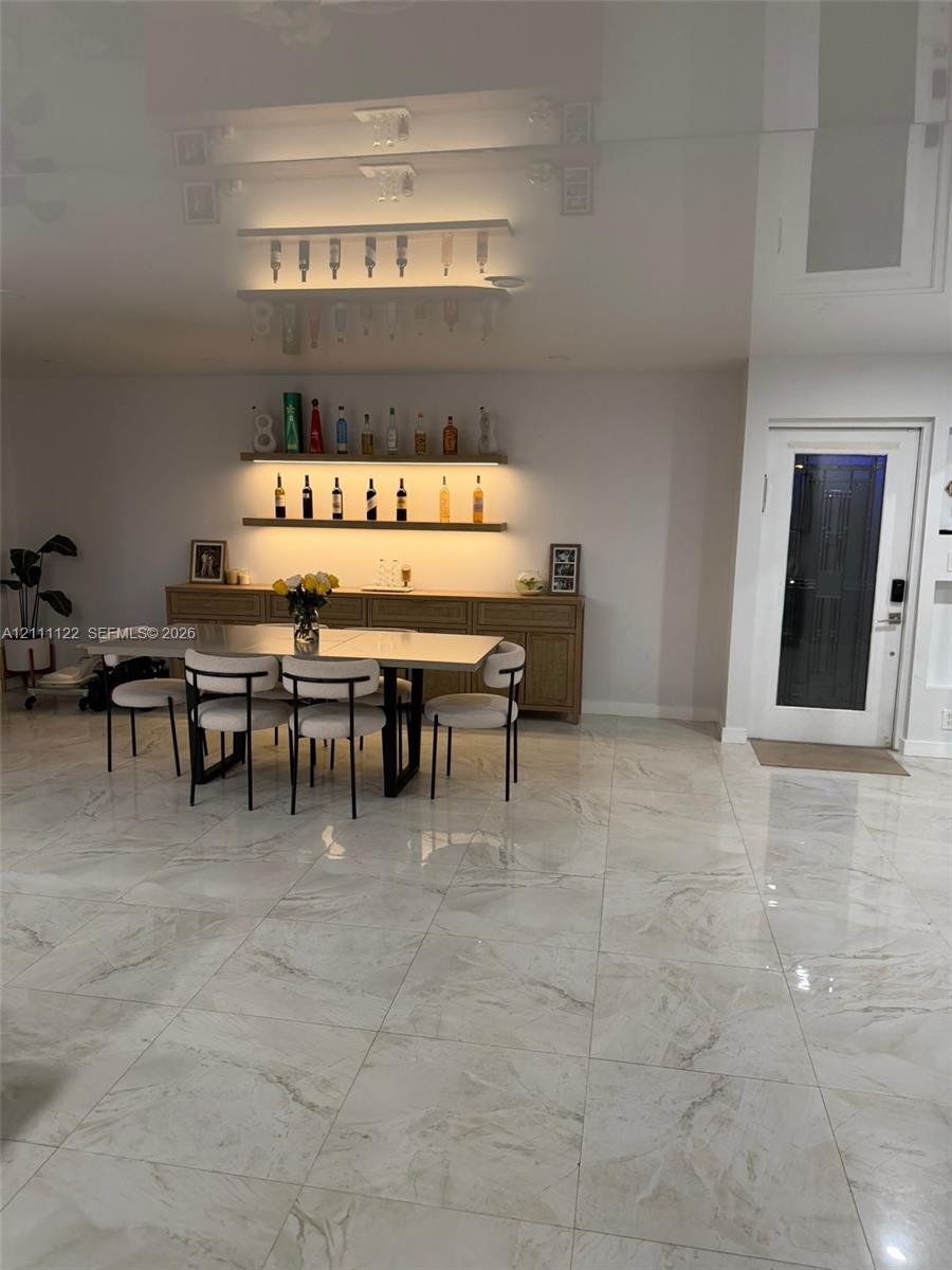 Large-format tile flooring, built-in wooden sideboard, dual recessed wall shelves with integrated lighting, and glass-paneled exterior door