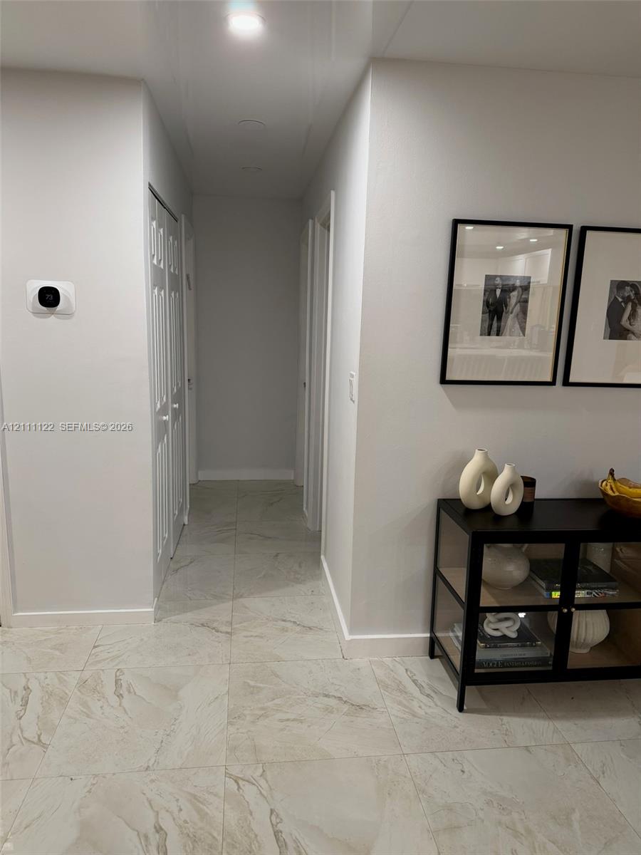 Large-format tile flooring, recessed ceiling lighting, and smart thermostat interface