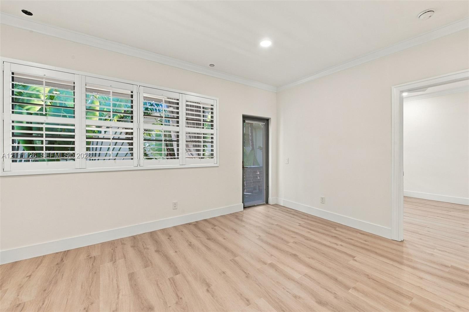 Interior space featuring light wood-finish flooring, plantation shutters, recessed lighting, and crown molding
