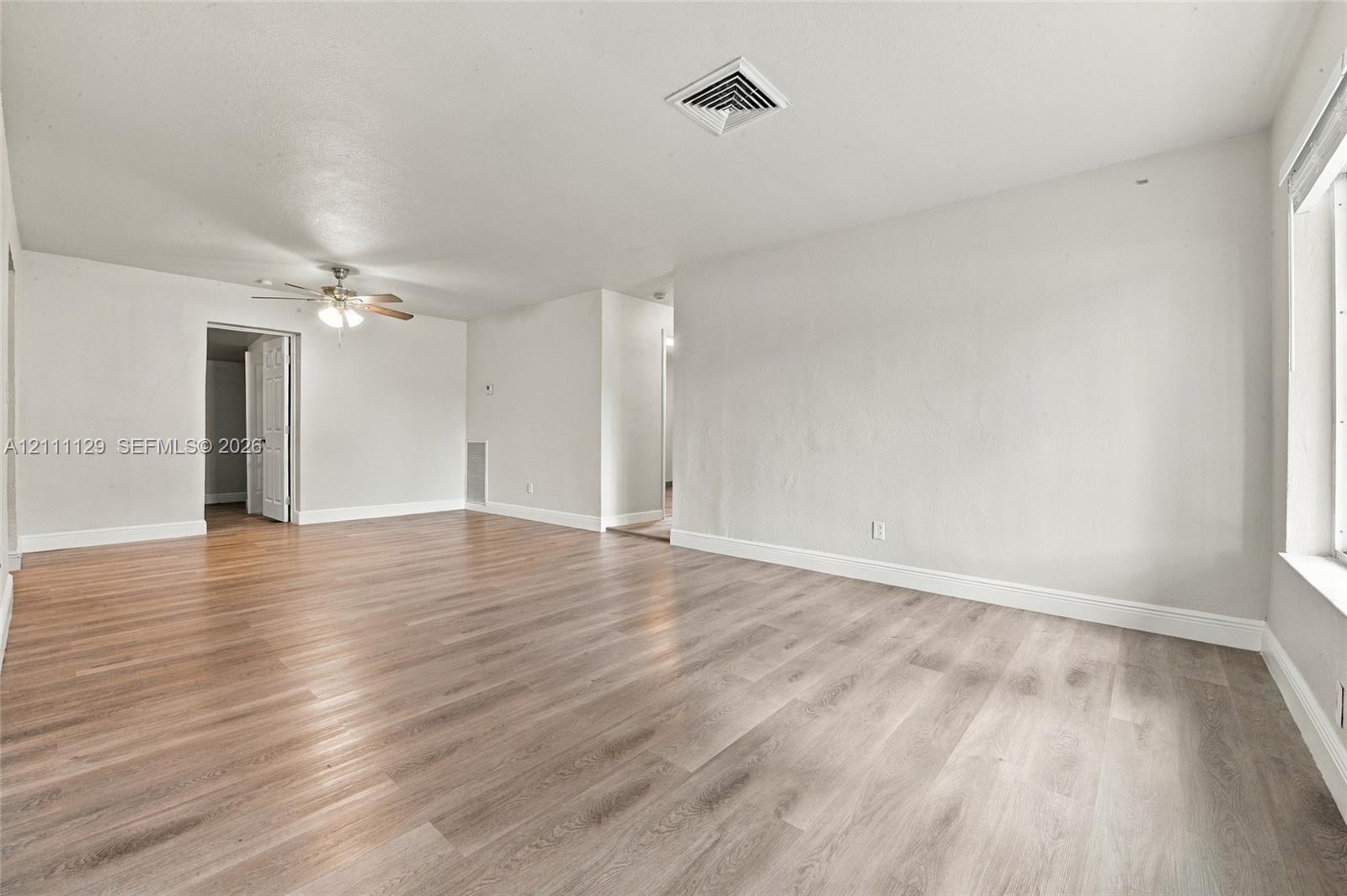 Interior space featuring wood-finish flooring, neutral wall paint, and a ceiling-mounted light fixture with a fan