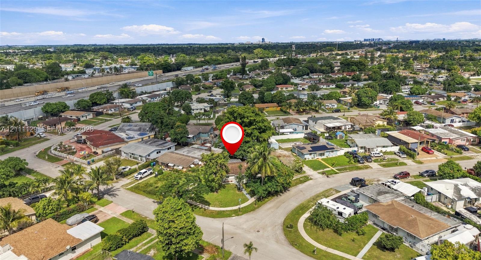 Aerial perspective of a corner lot property featuring mature shade trees, established landscaping, and paved street access within a residential neighborhood