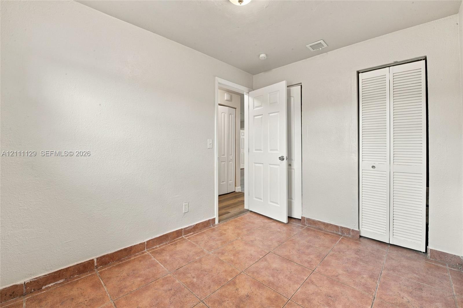 Room featuring tile flooring, neutral wall paint, and a bi-fold louvered closet door