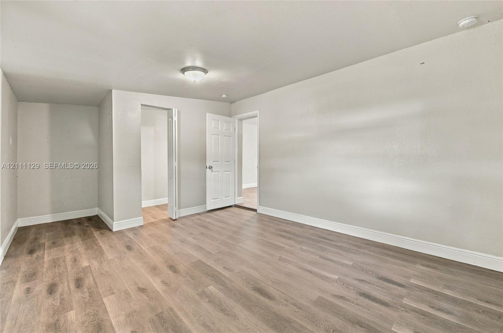 Interior space featuring wood-finish flooring, neutral wall paint, and a flush-mount ceiling light fixture