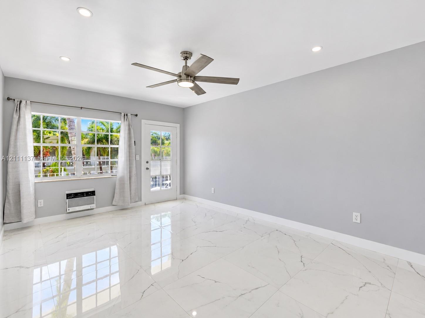 Large-format tile flooring with polished finish, recessed ceiling lighting, brushed metal ceiling fan with integrated lighting, multi-pane window, and exterior door with glass insert Large-format tile flooring with polished finish, recessed ceiling lighting, brushed metal ceiling fan with integrated lighting, multi-pane window, and exterior door with glass insert