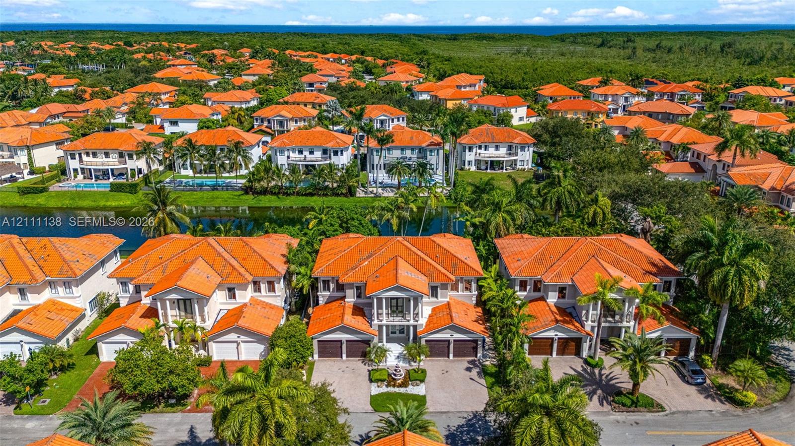 Aerial perspective featuring multi-story residences with terracotta-style tile roofing, paver driveways, and proximity to a canal