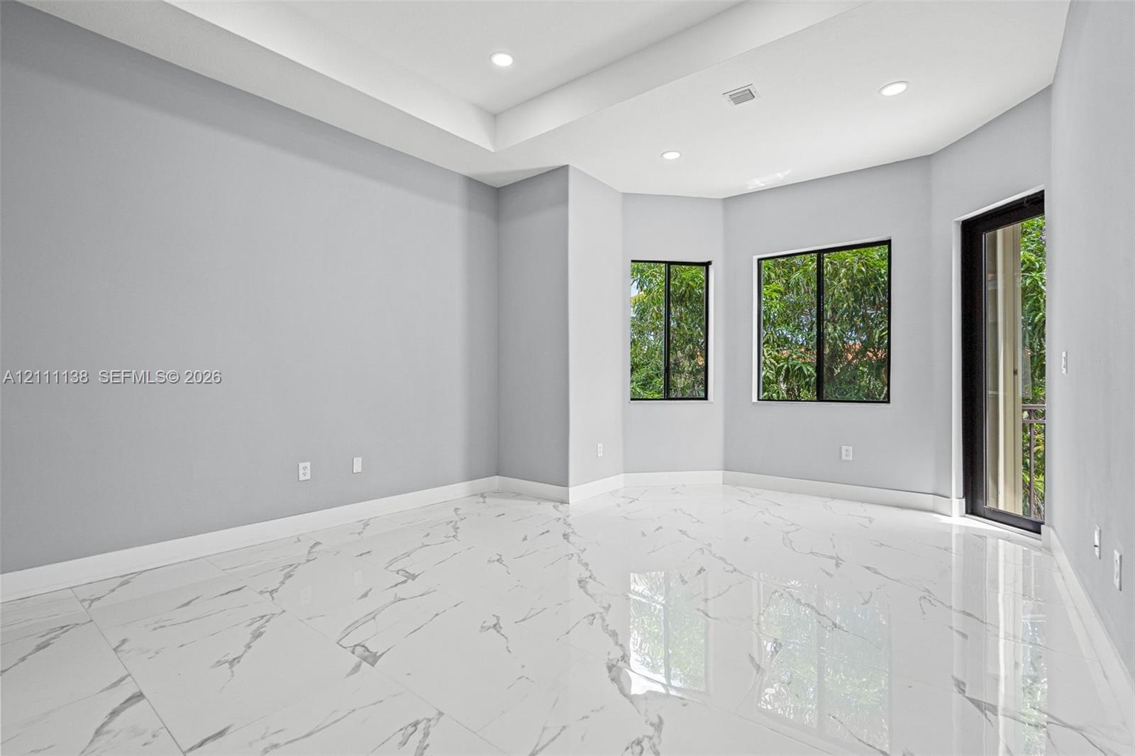 Polished tile flooring with marble-pattern veining, tray ceiling, recessed lighting, and large-paned windows
